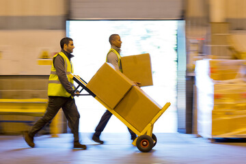 Workers carting boxes in warehouse