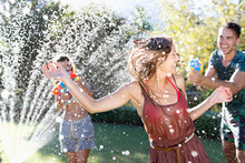 Friends Playing With Water Guns In Sprinkler