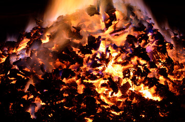 beautiful red hot glowing ember pile with colorful flames in winter night