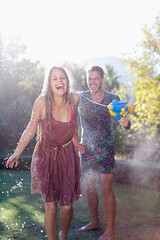 Wall Mural - Couple playing with water guns in backyard