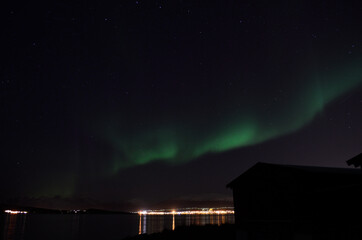 aurora borealis over cold fjord and mountain in autumn