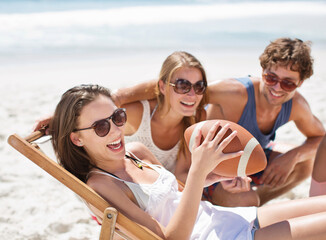 Smiling friends with football on beach