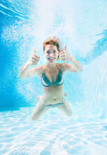 Woman Giving Thumbs Up Underwater In Swimming Pool