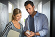 © Tom Merton/KOTO - Business people looking down at cell phone in corridor