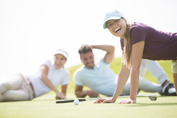 Wall Mural - Friends laying and laughing on golf course