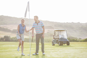 Wall Mural - Couple playing golf on course