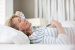 © Tom Merton/KOTO - Older woman listening to earphones on bed