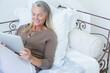 © Chris Ryan/KOTO - Senior woman using digital tablet on bed