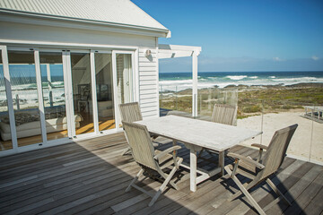 Table and chairs on balcony overlooking beach