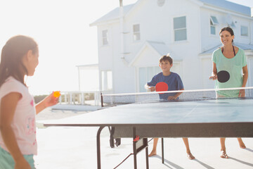 Family playing table tennis together outside house