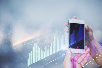 Double exposure of forex graph sketch hologram and woman holding and using a mobile device. Stock market concept.