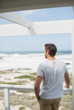 Man Looking At Ocean View From Balcony