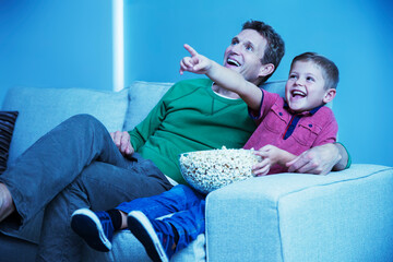 Father and son watching television in living room