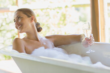 Woman Having Champagne In Bubble Bath