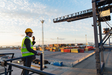 Worker using walkie-talkie near crane