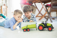 Brothers Playing With Toy Tractor On Floor