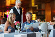 © Dan Dalton/KOTO - Man ordering meal at fancy restaurant table, waiter standing behind