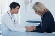 © Dan Dalton/KOTO - Female doctor consoling sad woman at desk in office