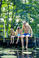 Wall Mural - Father and sons dangling feet in lake