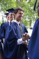 Wall Mural - University students congratulating one another after graduation ceremony