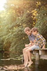 Wall Mural - Father and son dangling feet in lake