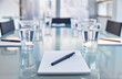 © Chris Cross/KOTO - Part of modern conference room table chairs, notepads, pens glasses water