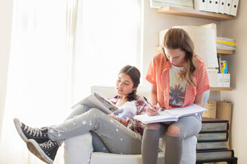 Two teenage girls doing homework in room