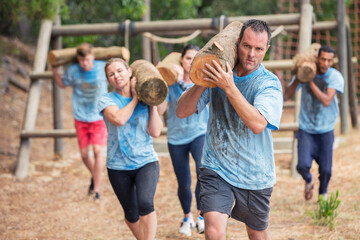 Wall Mural - Determined people running with logs on boot camp obstacle course