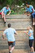 © Sam Edwards/KOTO - Teammates cheering man nearing wall on boot camp obstacle course