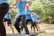 Determined people jumping tires on boot camp obstacle course