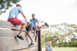 © Sam Edwards/KOTO - Teammates helping man over wall on boot camp obstacle course