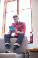 Wall Mural - Casual businessman with headphones and digital tablet in office window