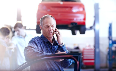 Wall Mural - Man talking on cell phone in auto repair shop