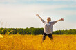Exuberant senior woman with arms outstretched in sunny rural field