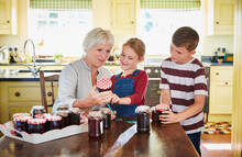 Grandmother Canning Jam With Grandchildren In Kitchen