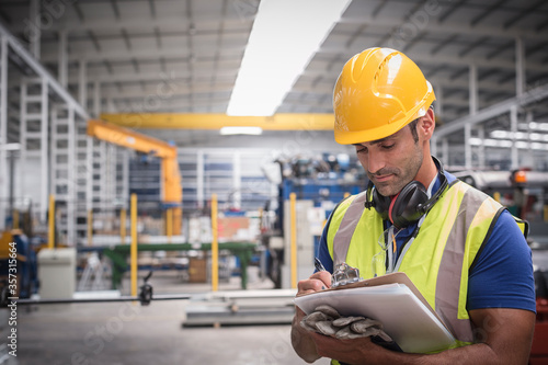 Cuadros en Lienzo Male worker writing on clipboard in factory