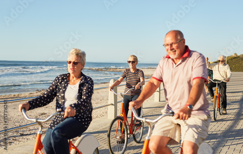 Cuadros en Lienzo Active senior tourist friends bike riding on sunny boardwalk along ocean