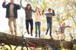 © Tom Merton/KOTO - Enthusiastic family jumping from fallen log over bicycles
