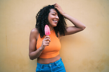 Afro woman enjoying summertime and eating an ice-cream