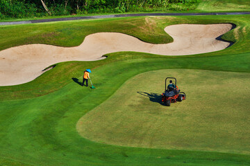 Wall Mural - View of golf course with green grass. Sand bunkers at the beautiful golf course at the ocean side early morning.