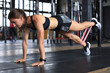 © ty - Muscular woman on a plank position use fitness gum.
