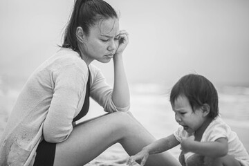 Black and white photo of a bored mom looking over her daughter at the beach