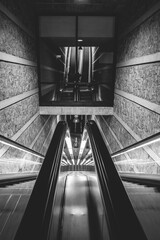 Sticker - Vertical grayscale shot of an escalator inside a building