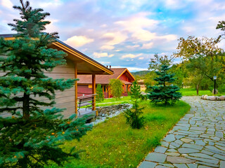 Wall Mural - Wooden cottages on the background of nature. Landscape design of the territory. Stay in the fresh air. A beautiful place for a country holiday. Cottage rentals.