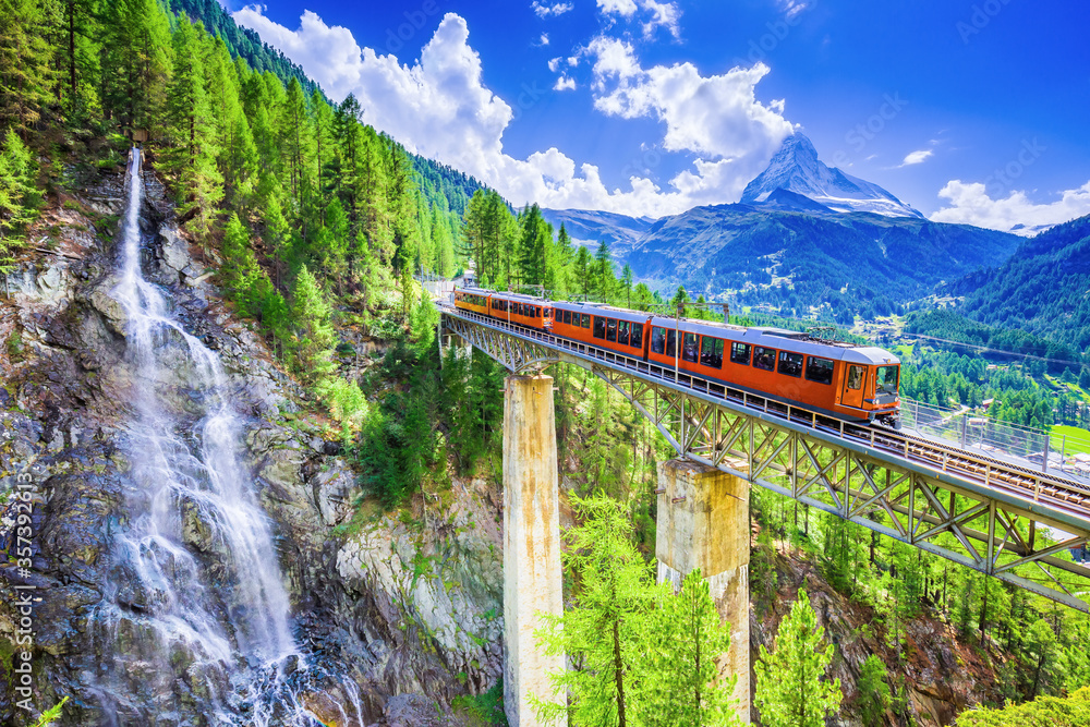Zermatt, Switzerland. Gornergrat tourist train with waterfall, bridge and Matterhorn. Valais region. - obrazy, fototapety, plakaty 