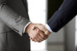 © rogerphoto - Business people in office suits standing and shaking hands, close-up. Business communication concept. Handshake and marketing