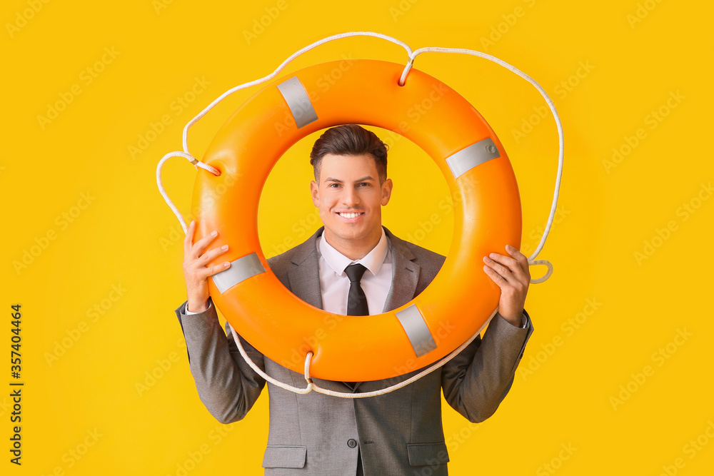 Young businessman with lifebuoy on color background