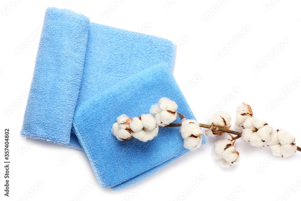Cotton flowers and soft towels on white background
