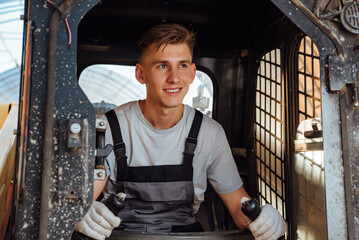 Wall Mural - A man in overalls driving a tractor. Worker sitting on his tractor