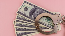 Iron Handcuffs And Money On A Pink Background